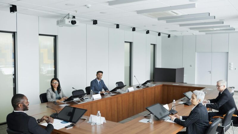 Ondernemers bespreken AI implementatie kosten tijdens zakelijke vergadering met laptops en documenten
