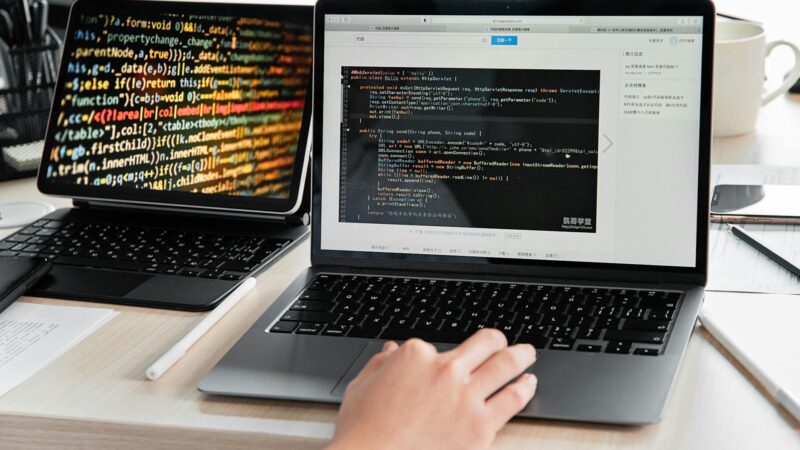 Developer bekijkt AI-gegenereerde code op twee schermen, developer rol AI zichtbaar in workflow