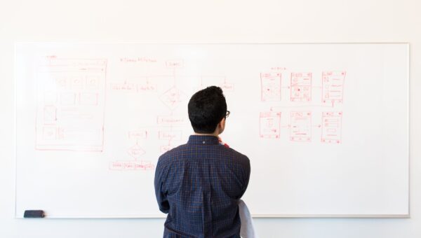 UX designer schetst wireframes op whiteboard voor webdesign disciplines uitleg